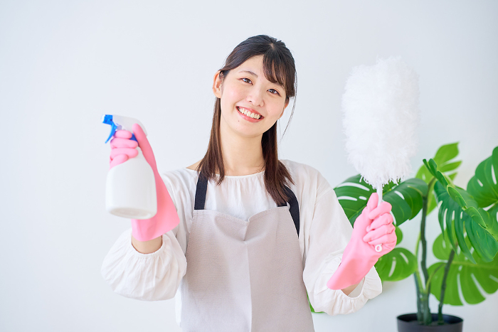 Young Japanese woman in apron holding cleaning tools (People)