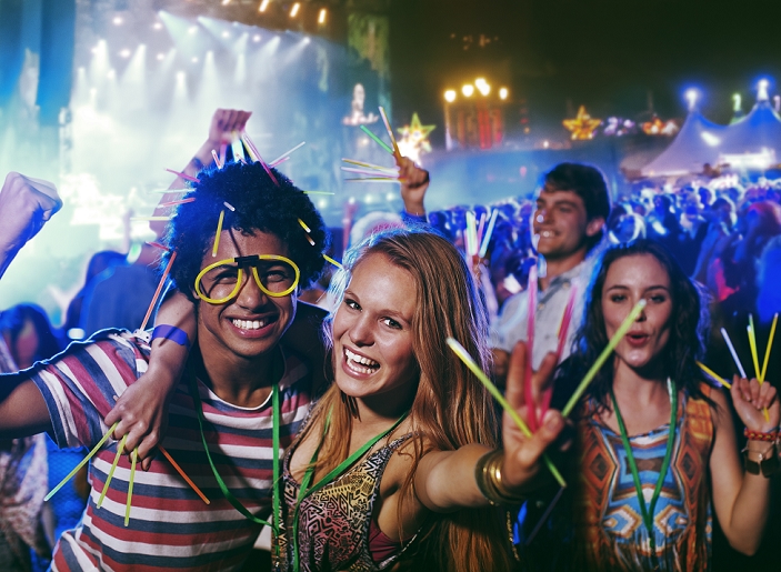 Young people attending a music festival Portrait of friends with glow sticks at music festival