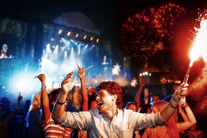 Young people attending a music festival Fans with fireworks at music festival