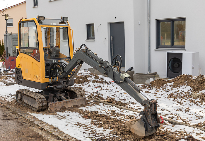 Small excavator parked in front of a new building Small excavator parked in front of a new building, by Zoonar ROBERT JANK