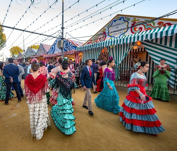 Women in colourful flamenco dresses, in front of marquees, casetas, decorated street, Feria de Abril, Sevilla, Andalusia, Spain, Europe, by Mara Brandl