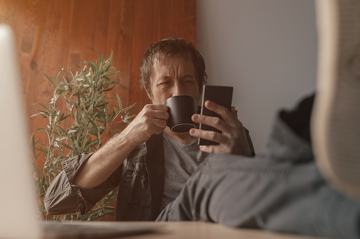 Man using smartphone and drinking coffee Man using a smartphone and drinking coffee., by IGOR STEVANOVIC   SCIENCE PHOTO LIBRARY