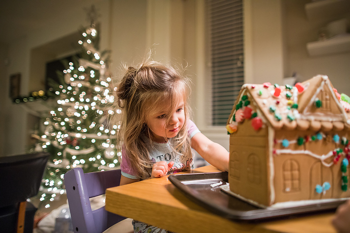 Young creative girl works hard to decorate her gingerbread house, by Cavan Images / Christopher Kimmel / Alpine Edge Photography