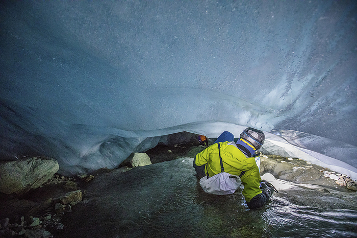 Explorer squeezing into confined area below a glacier, by Cavan Images / Christopher Kimmel / Alpine Edge Photography