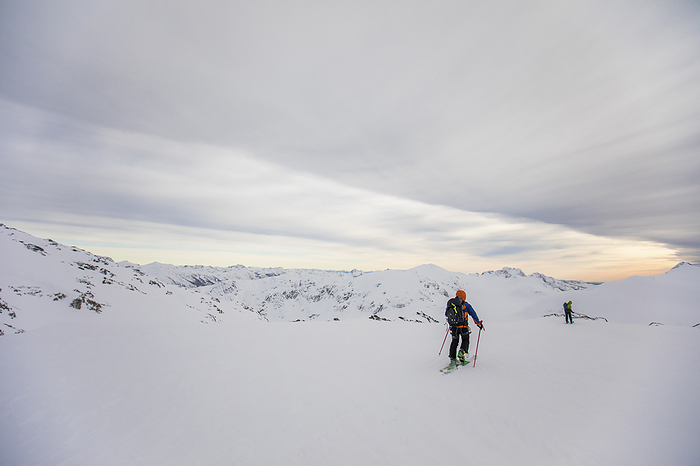 Two skiers skin over flat glacier, high mountain range, by Cavan Images / Christopher Kimmel / Alpine Edge Photography