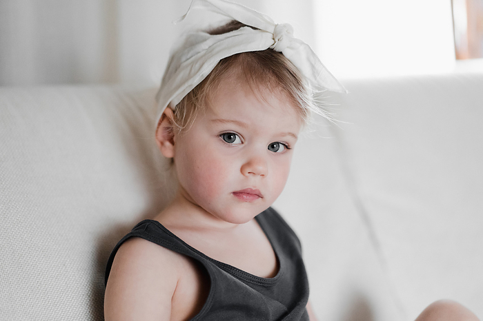 Stylish little girl aged 2 years looks seriously, close up, by Cavan Images / Liza Zavialova