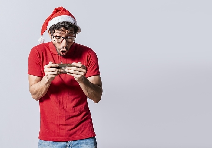 Surprised people watching a christmas promotion on the phone. Amazed man looking at a christmas offer online, Guy looking at a christmas promo on phone. Online christmas special offers concept, by Isai Hernandez