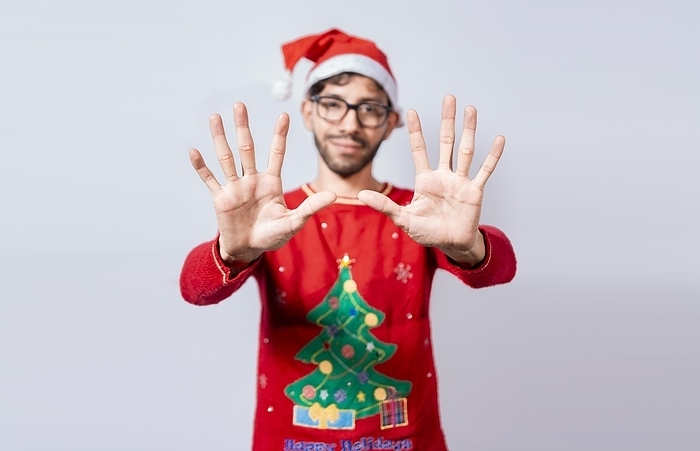 Man in christmas hat counting number ten with fingers. Christmas young man counting number ten with hands. Concept of man in christmas costume counting number ten isolated, by Isai Hernandez