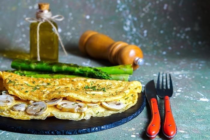 Mushroom omelette with wild asparagus on a slate, with cutlery, pepper and extra virgin olive oil, by jose hernandez antona