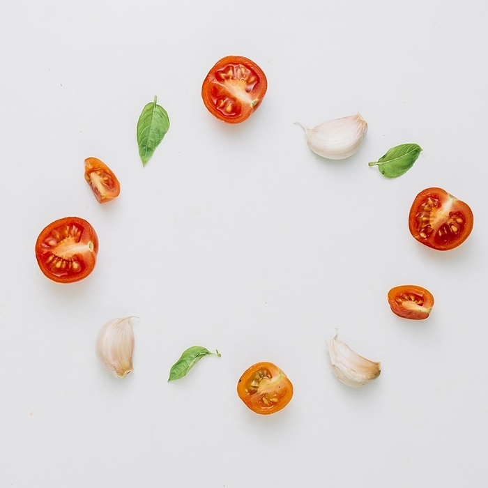 Circular frame made with cherry tomatoes basil garlic cloves white background. Resolution and high quality beautiful photo, by Oleksandr Latkun