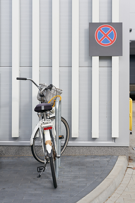 parked bicycle at a supermarket, behind it a no stopping sign on the wall parked bicycle at a supermarket, behind it a no stopping sign on the wall, by Zoonar HEIKO KUEVERL