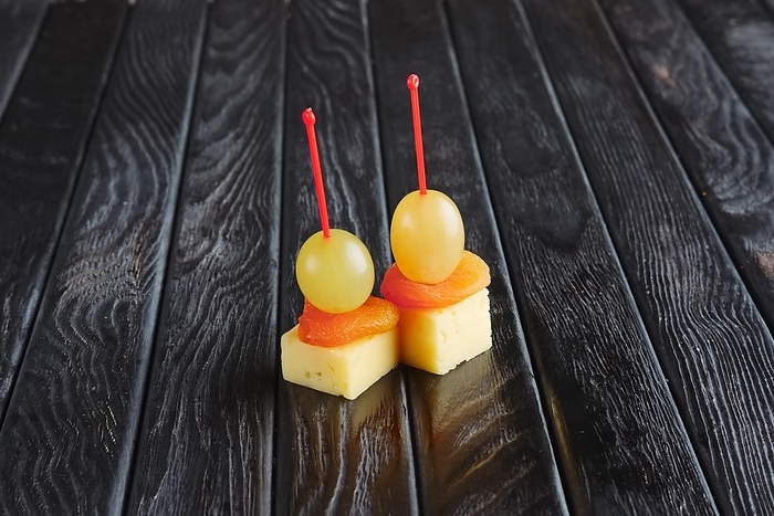 Appetizer for reception. Cheese, dried apricot and grape on skewer