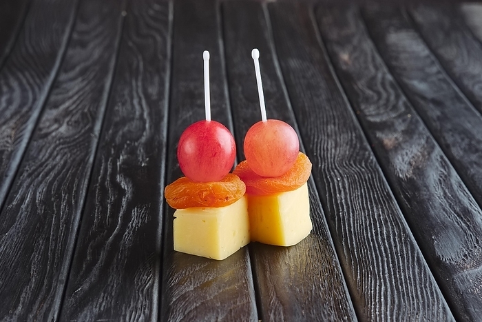 Appetizer for reception. Cheese, dried apricot and grape on skewer