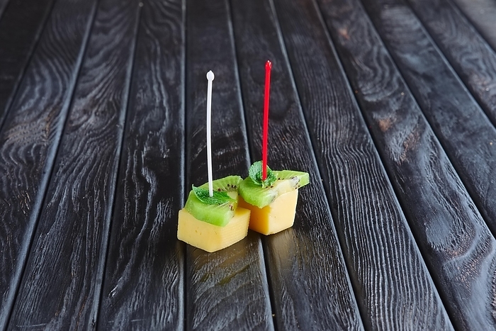 Appetizer for reception. Cheese, kiwi and leaf of mint on skewer