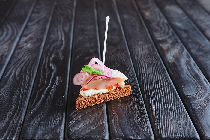 Appetizer for reception. Small sandwich with herrings, cheese and onion on skewer