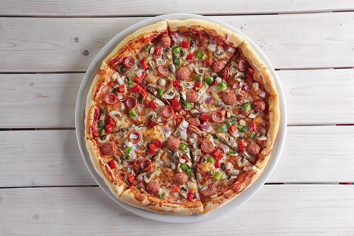 Pizza with sausage, ham, tomato, zucchini and paprika