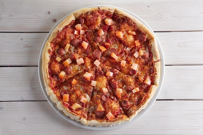 Pizza with sausage, ham, tomato, zucchini and paprika