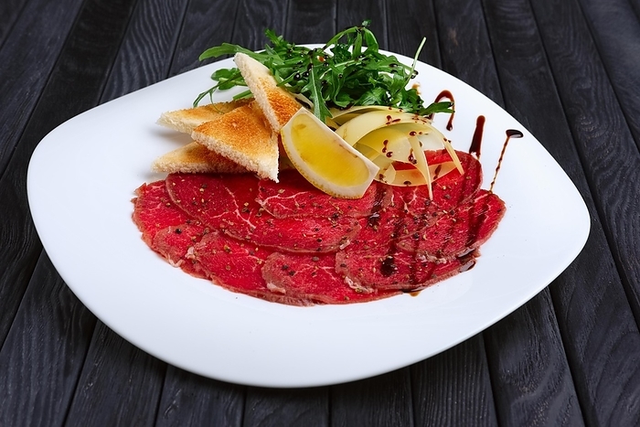 Beef carpaccio with cheese, white bread toasts and lemon