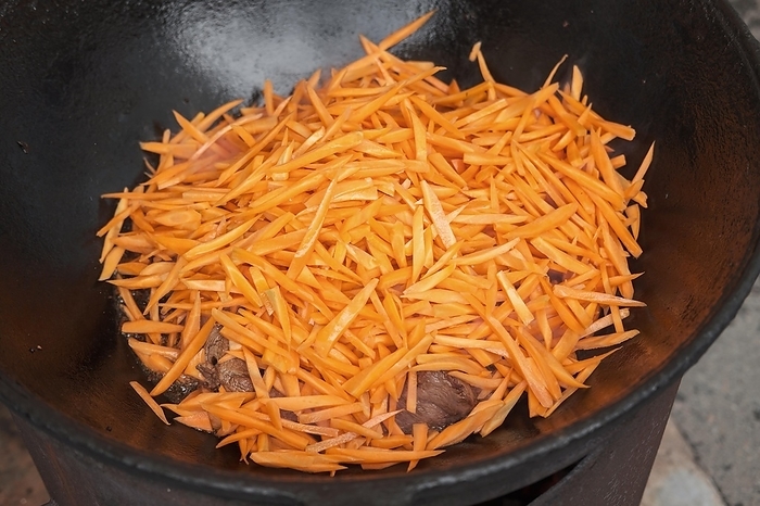 Meat orange carrot and onions in cauldron. The making of pilaf, step by step