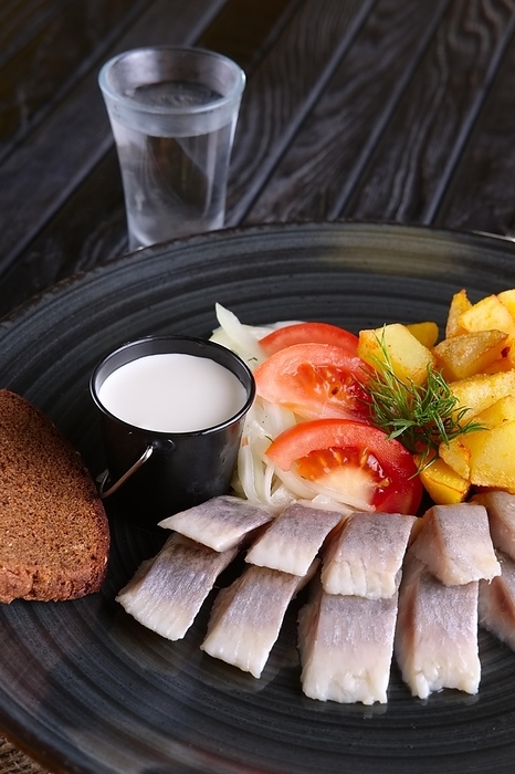 Snack for vodka, pickled herring, fried potato, onion and tomato