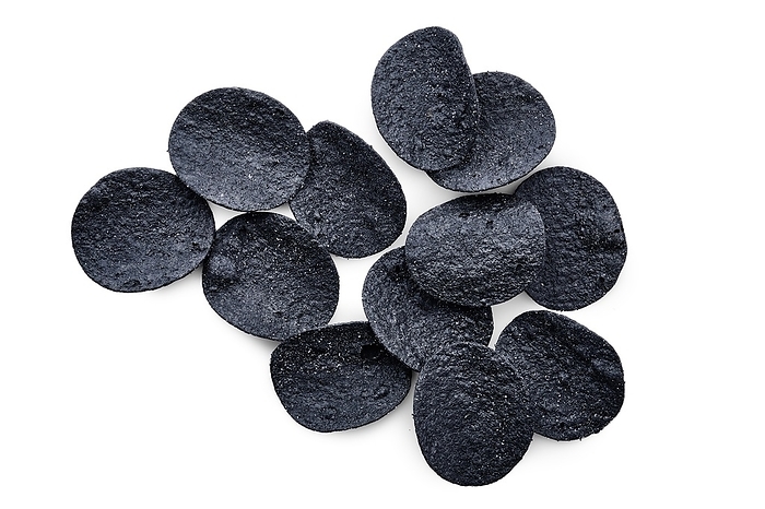 Overhead view of black crispy spicy potato chips isolated on white background
