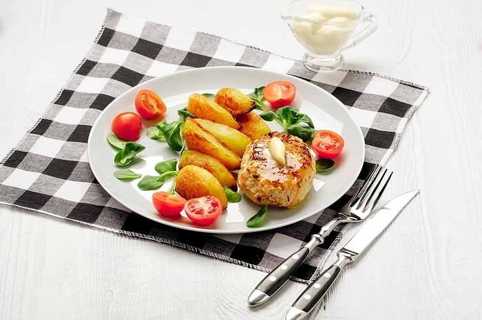 Fried chicken cutlet with potato slices served with tomato cherry and corn salad. Traditional belorussian food, roasted minced meat and potato