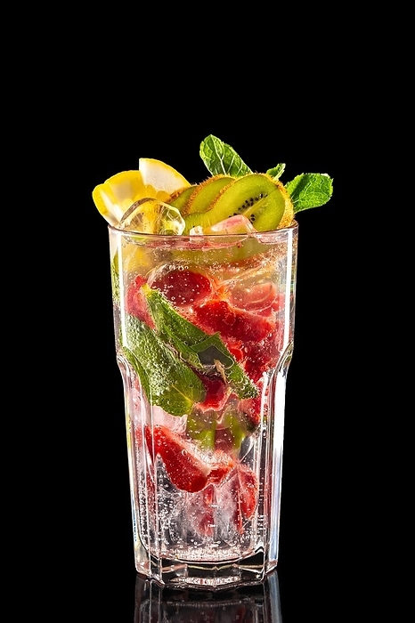 Glass of raspberry, kiwi and lemon ice lemonade isolated on black background