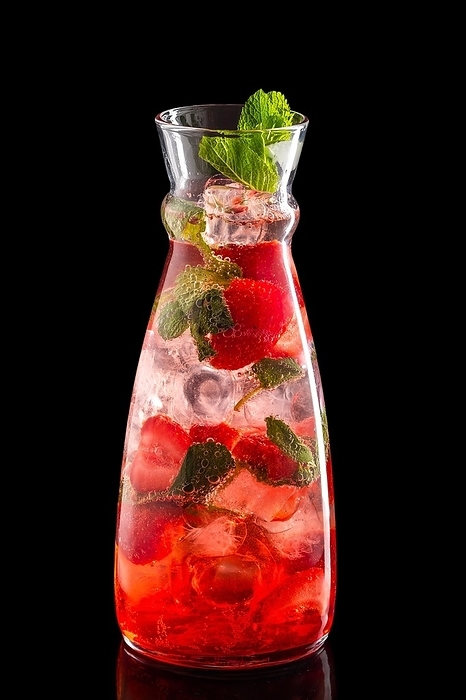 Pitcher with strawberry and mint ice lemonade isolated on black background