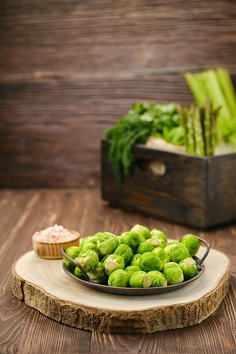 Fresh Brussels sprouts on wooden cutting board (focus on foreground)