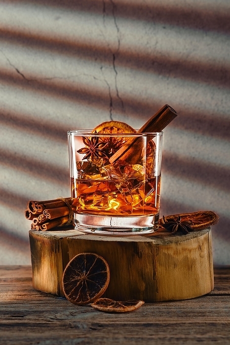 Cold cocktail with brandy and orange liquor, cinnamon and star anise on wooden block