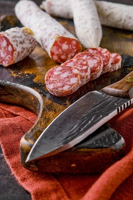 Fermented air-dried salami on wooden cutting board cut on slices, closeup view