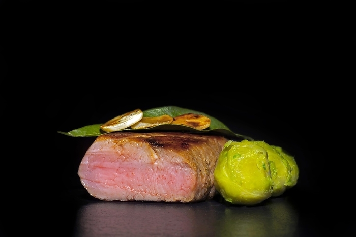 Roasted pork fillet with garlic and Brussels sprouts, food photography with black background