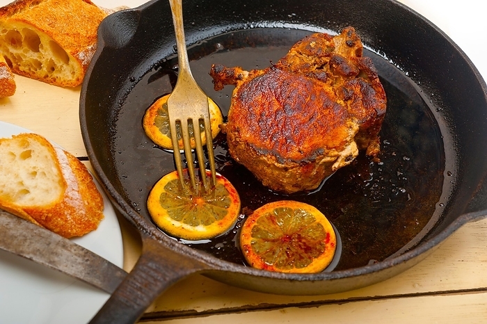 Pork chop seared on iron skillet with lemon and spices seasoning