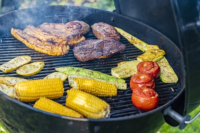 Barbecue in the garden, there are steaks on the grill, but also vegetarian food like tomatoes, corn and courgette, Münsingen, Baden-Württemberg, Germany, Europe