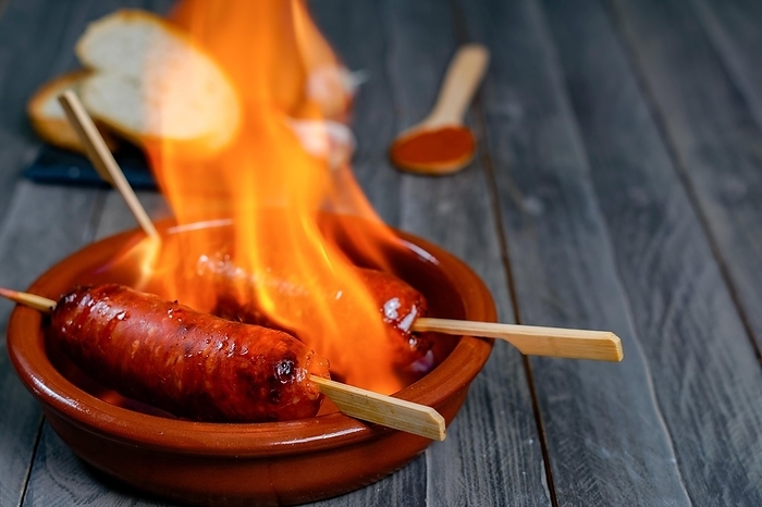 Chorizo grilled, chorizo al infierno, in a clay pot with bread, olives and paprika, a typical dish of Spanish food