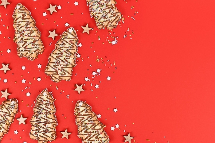 Christmas tree shaped cookies with sugar sprinkles on red background