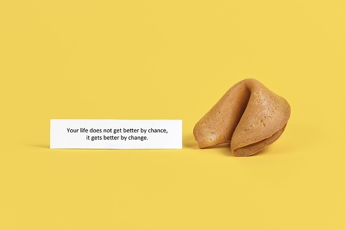 Fortune cookie note saying Life does not get better by chance, it gets better by change on yellow background