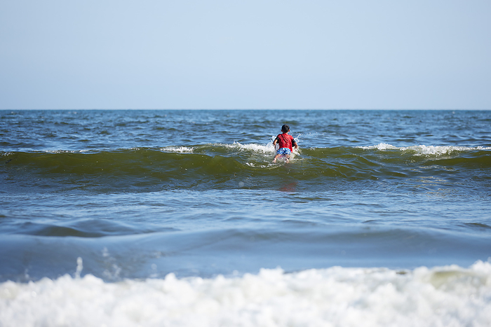 Back view of a boy surfing