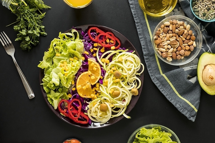 Overhead view garnished healthy salad plate with drifts fork against black background