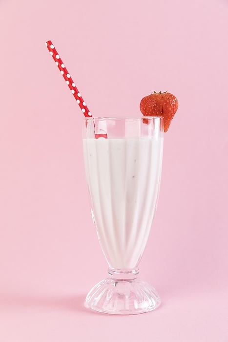 Close up strawberry milkshake glass with pink background