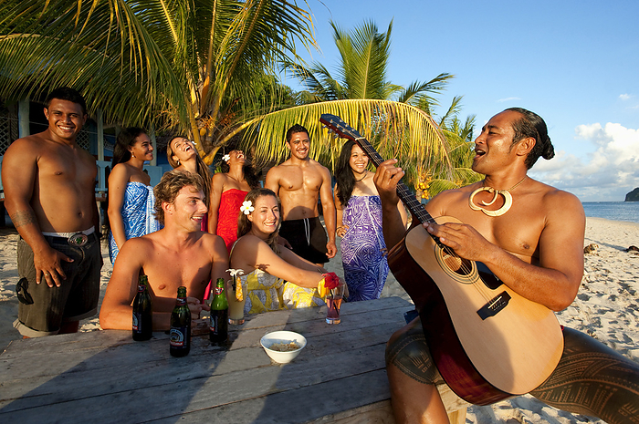 Tourists Singing Along With A Samoan Guitar Player On The Beach; Upulu Island, Samoa, by David Kirkland / Design Pics
