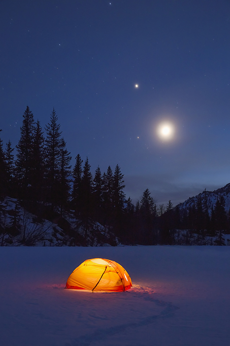 Nighttime View Of A Lit Tent On A Snow Covered Trail Lake With The Moon, Stars, And Planets Overhead, Moose Pass, Kenai Peninsula, Southcentral Alaska, by Kevin G. Smith / Design Pics