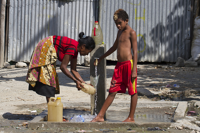 Woman And Boy By A Water Pump; Manatuto, East Timor, by Peter Langer / Design Pics