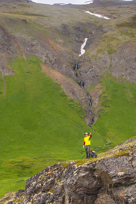 A Man Hiking In Hanging Valley Takes A Selfie With A Waterfall In The Background In South Fork Near Eagle River, Southcentral Alaska, Summer, by Michael Jones / Design Pics