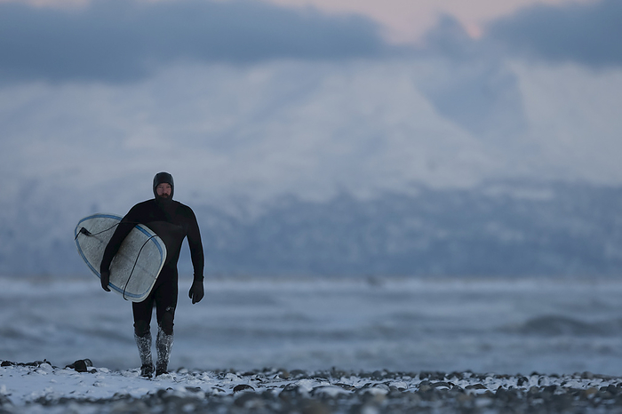America Man with surfboard walking on the snow on Homer beach in winter, South central Alaska  Homer, Alaska, United States of America, by Scott Dickerson   Design Pics