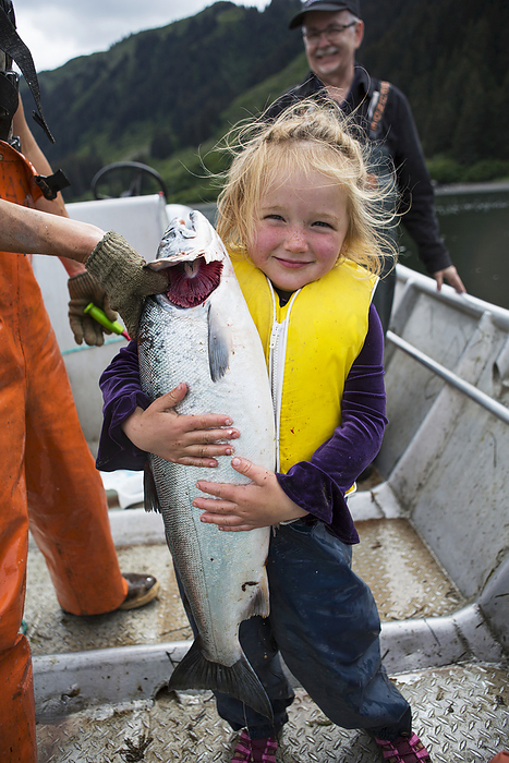 America Young girl holding a salmon in a set net skiff, South central Alaska  Seldovia, Alaska, United States of America, by Scott Dickerson   Design Pics