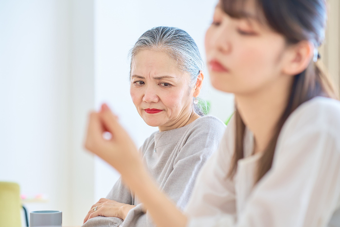 Senior Japanese woman looking at a young woman with a stern expression (People)
