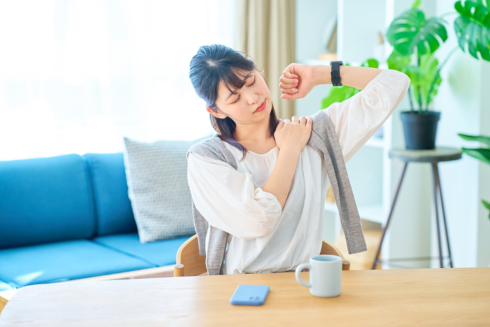 A young Japanese woman stretches in a casual space (People)