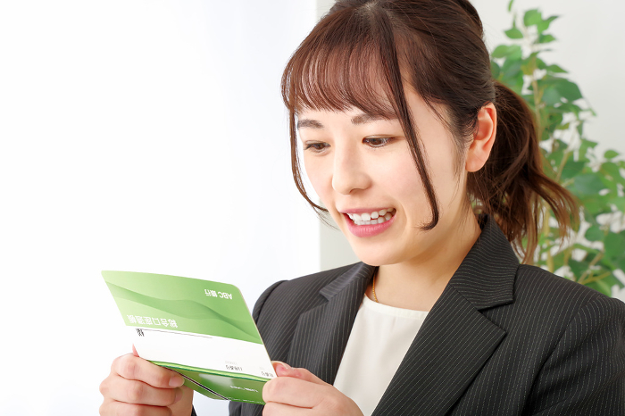 A woman with a happy expression on her face when she sees the bankbook.