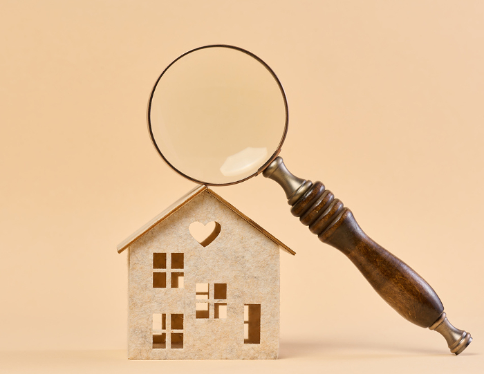 Wooden house and a magnifying glass, representing the concept of real estate purchase, rental growth, and mortgage interest Wooden house and a magnifying glass, representing the concept of real estate purchase, rental growth, and mortgage interest
